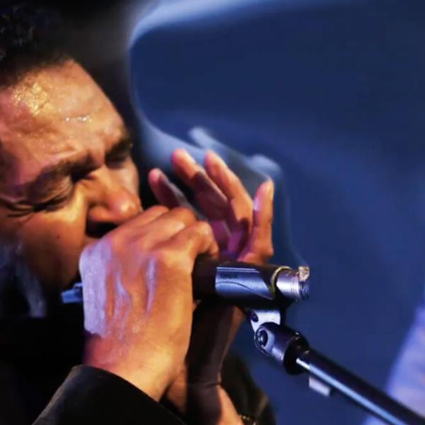 an African American man plays a harmonica
