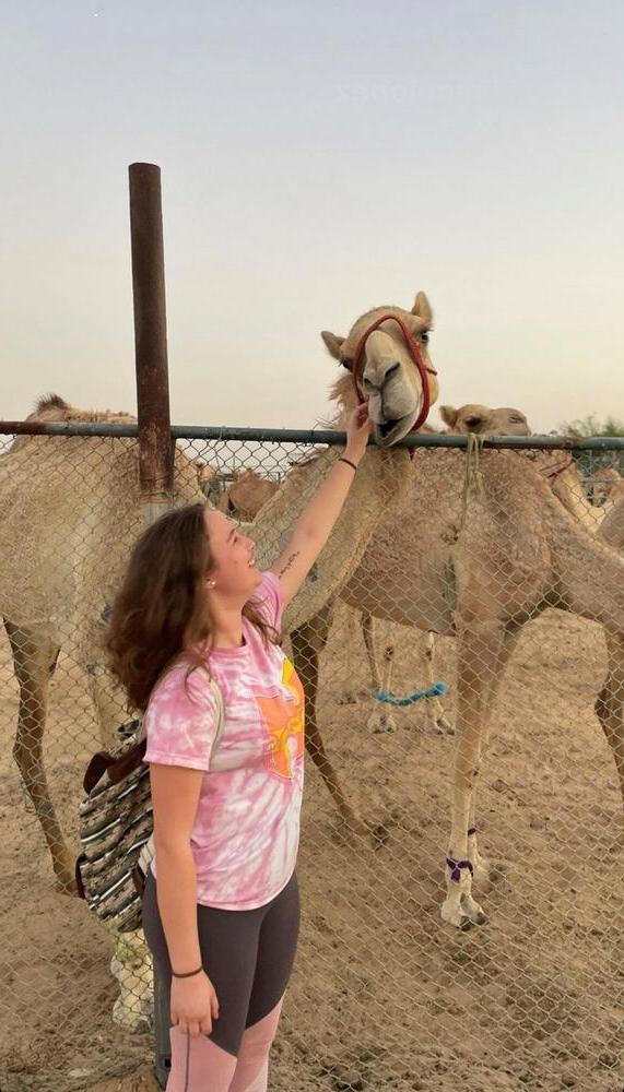 一位年轻女子抚摸着一只骆驼
